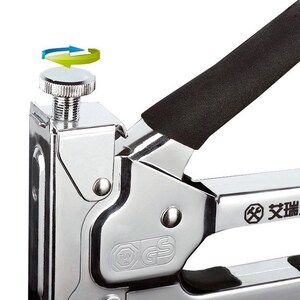 May include: Close-up of a chrome-plated staple gun with a black handle. The gun features a silver adjustment knob and a black grip. The image shows a detail of the tool's mechanism and design.