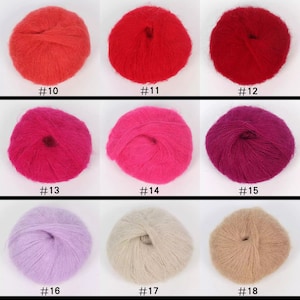 May include: Nine skeins of yarn in various colors, including red, pink, purple, lavender, and beige. Each skein is wound into a ball shape and is displayed on a white background.