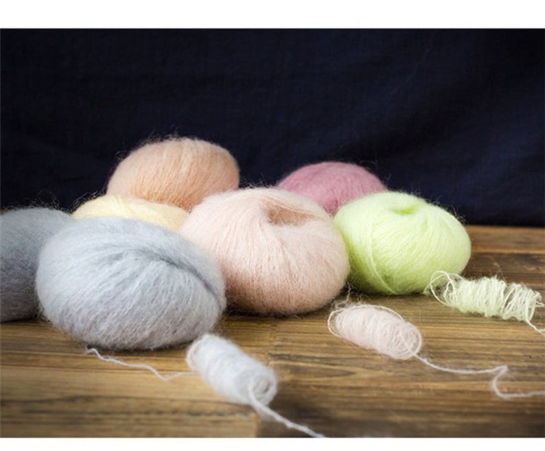 May include: A collection of eight balls of yarn in various pastel colors, including pink, peach, light blue, yellow, and green. The yarn is soft and fluffy, perfect for knitting or crocheting.