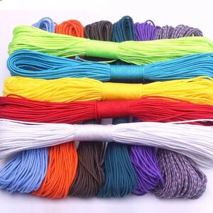 May include: A collection of 14 spools of paracord in various colours, including green, blue, yellow, red, white, orange, brown, teal, purple, and multi-coloured.