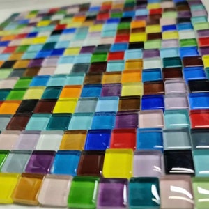 Puede incluir: Primer plano de un mosaico colorido hecho de pequeños azulejos cuadrados de vidrio. Los azulejos están dispuestos en un patrón de cuadrícula y presentan una variedad de colores, incluyendo azul, verde, rojo, amarillo y morado.