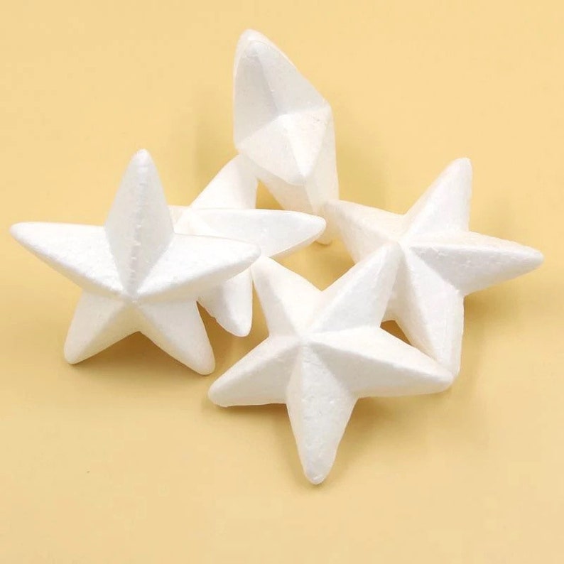 May include: Four white foam star shapes, each with five points. The stars are arranged in a pile, with one star on top of the others.