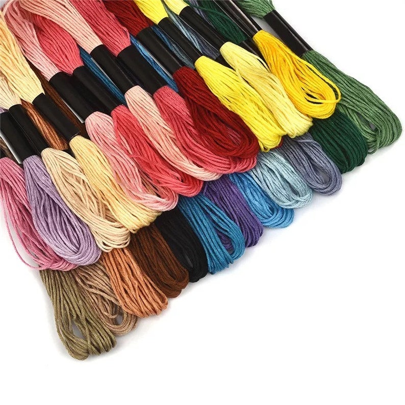 Puede incluir: Una colecci&oacute;n de carretes de hilo de bordar de colores, dispuestos en forma de abanico. El hilo es de varios colores, incluyendo rojo, azul, verde, amarillo y morado.
