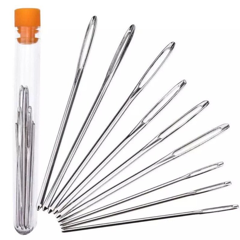 May include: A set of 10 assorted needles in a clear plastic tube with an orange lid. The needles are arranged in a fan shape.