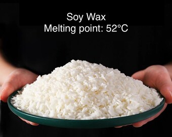 Puede incluir: Primer plano de copos de cera de soja blanca en un bol verde. El texto "Soy Wax Melting point: 52°C" es visible sobre el bol.