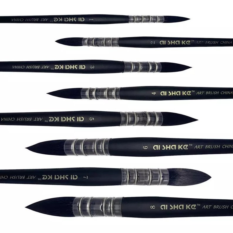 Op de afbeelding: Een set van acht zwarte penselen horizontaal gerangschikt, elk met een puntige donkere borstelpunt, een zilverkleurige metalen huls met geribbelde details en een zwarte steel bedrukt met de tekst AI SHA KE ART BRUSH CHINA en een maatnummer.
