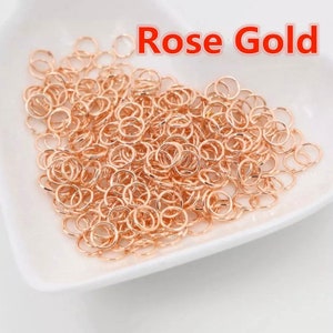 Peut inclure: Un grand tas de anneaux de saut en or rose. Les anneaux sont petits et ronds, et ils sont parfaits pour la fabrication de bijoux.