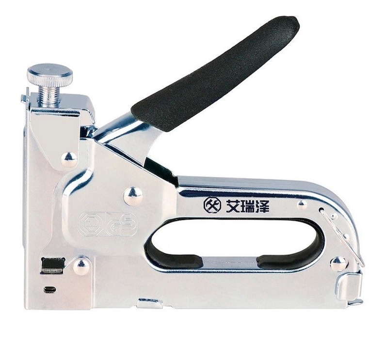 May include: A silver-colored staple gun with a black handle and a silver adjustment knob. The tool has a curved handle and a rectangular body. The text "艾瑞泽" is printed on the side of the tool.