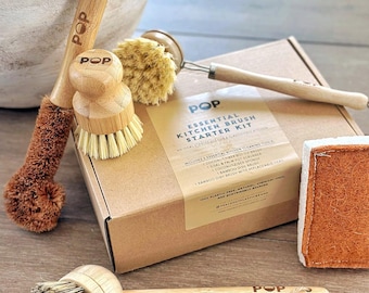 May include: A collection of kitchen cleaning tools, including brushes, a sponge, and a box set. The brushes have wooden handles and natural bristles. The box set is labeled "Essential Kitchen Brush Starter Kit" with the brand name "POP".