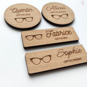 Peut inclure: Quatre étiquettes de nom en bois avec les noms Quentin, Alicia, Fabrice et Sophie. Chaque étiquette a une paire de lunettes et le mot "Opticien" ou "Opticienne" en dessous.