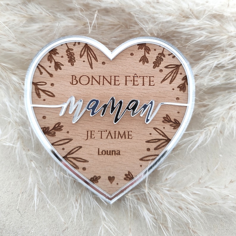 Puede incluir: Una placa de madera en forma de coraz&oacute;n con un borde plateado. La placa tiene un dise&ntilde;o floral y el texto "Bonne F&ecirc;te Maman Je T'aime Louna".