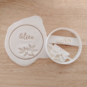 May include: White plastic cookie cutters with the names "Alice" and "Emily" and a leaf design.