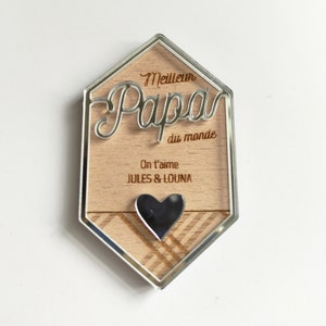 May include: A wooden plaque with a silver border and a heart-shaped cutout. The plaque reads "Meilleur Papa du monde" and "On t'aime JULES & LOUNA".