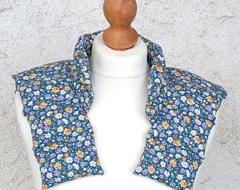 Puede incluir: Una envoltura de cuello floral azul con un patrón floral blanco y naranja. La envoltura de cuello está hecha de tela y está rellena de arroz o semillas de lino. Se puede calentar en el microondas o enfriar en el congelador para fines terapéuticos.
