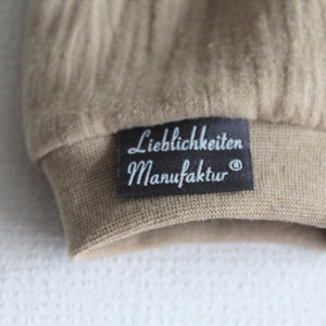 May include: A brown fabric garment with a black label that reads "Lieblichkeiten Manufaktur" with a registered trademark symbol.