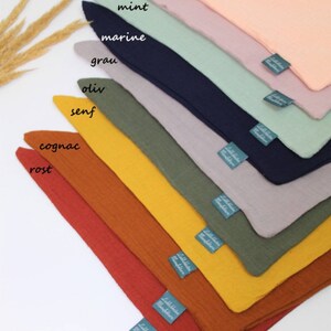 May include: A set of ten fabric squares in various colors, including apricot, mint, gray, olive, and rust. Each square has a small label with the color name written in German.