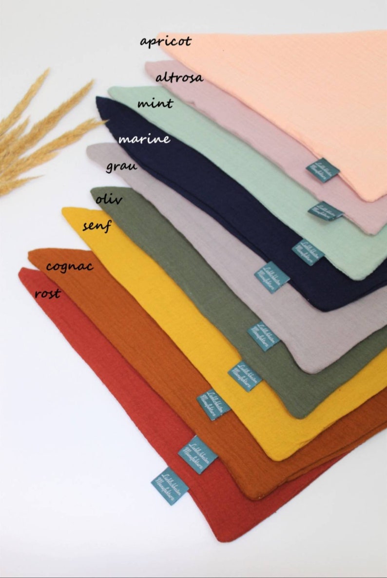 May include: A set of ten fabric squares in various colors, including apricot, mint, gray, olive, and rust. Each square has a small label with the color name written in German.