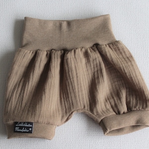 May include: Brown baby bloomers with a ribbed texture and a black label that says "Lieblichkeiten Manufaktur".