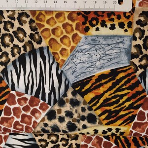 Può includere: Un tessuto colorato con un design a patchwork che presenta varie stampe di animali, tra cui leopardo, zebra, tigre e giraffa. Il tessuto è un mix di marrone, nero, bianco, arancione e blu.