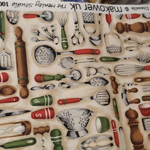 Könnte beinhalten: Cremefarbener Stoff mit einem sich wiederholenden Muster von Küchenutensilien. Das Design umfasst Nudelrollen, Schneebesen, Löffel, Messer und Messbecher in Braun, Rot, Grün und Silber. Der Text "makower uk" und "100% Cotton" ist sichtbar.