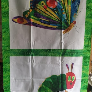 Op de afbeelding: Tweedelig doek met illustraties uit "De kleine rupsje-nou-en". Het bovenste paneel toont een kleurrijke vlinder met blauwe, gele en rode details. Het onderste paneel toont een groene rups met een rode kop en grote ogen.