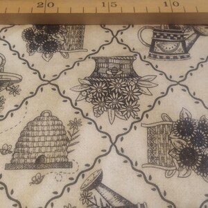 Könnte beinhalten: Cremefarbener Stoff mit einem sich wiederholenden Muster von Gartenelementen in Schwarz. Das Design umfasst Gießkannen, Bienenstöcke, Blumenkörbe und ein gitterartiges Rankenmuster. Geeignet für Bastelarbeiten oder Heimdekoration.