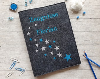 Könnte beinhalten: Grauer Filzordner mit blauer Stickerei von Sternen und dem Text "Zeugnisse Florian".
