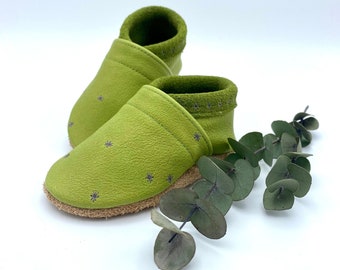 May include: A pair of green leather baby shoes with a star pattern. The shoes are soft and flexible, perfect for little feet.