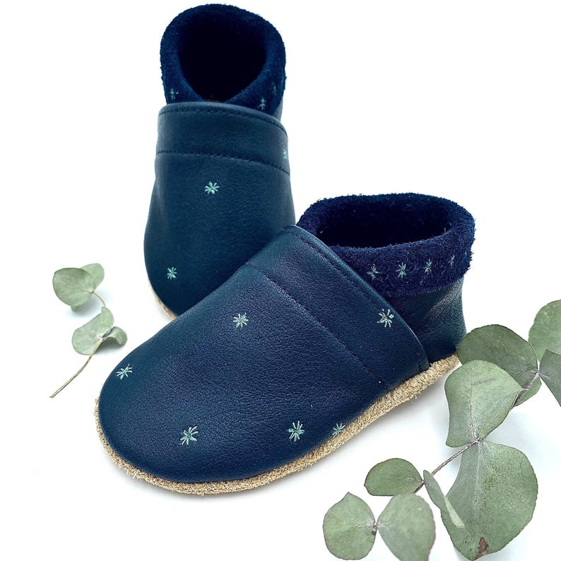 Die liebevoll handgefertigten Kinderschuhe mit Sternstickerei bringen den Zauber des Nachthimmels direkt an die Füße deines kleinen Schatzes. Hier in der Farben Blau mit Eukalyptus bestickt.