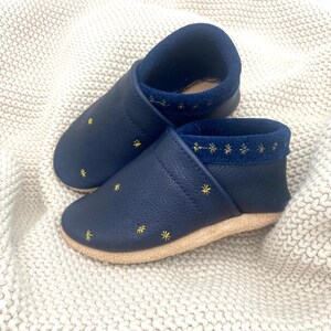 Mit liebevoll gestalteten, funkelnden Sternen verziert, bieten diese Schuhe nicht nur Komfort, sondern auch einen Hauch von Magie.