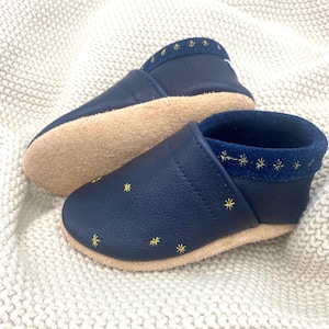 Die Kinderschuhe mit Sternstickerei sind perfekt für kleine Sternenfans. Mit liebevoll gestalteten, funkelnden Sternen verziert, bieten diese Schuhe nicht nur Komfort, sondern auch einen Hauch von Magie. Hier in Blau mit Gold bestickt.