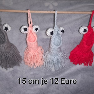 Könnte beinhalten: Drei gehäkelte Hängeschmuckstücke mit Fransen. Jedes Ornament ist tropfenförmig mit einem Gesicht und schwarzen Augen. Die Ornamente sind grau, rosa und rot. Der Text "15 cm je 12 Euro" befindet sich am unteren Rand des Bildes.