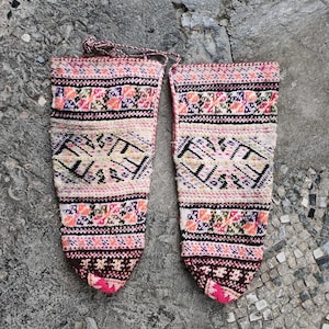 Puede incluir: Par de calcetines de punto con estampado geométrico en rosa, blanco y negro. Los calcetines tienen un ribete rojo y rosa en la parte superior e inferior.