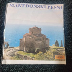 Könnte beinhalten: Ein Vintage-Schallplattencover mit einem Kirchengebäude vor blauem Himmel und Wasser im Hintergrund. Der Albumtitel lautet "Makedonski Pesni" und das Label ist "ETNO".