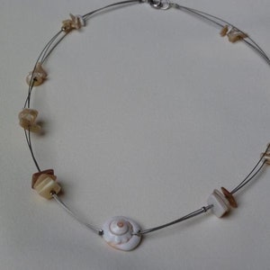 May include: A silver necklace with a white seashell pendant and brown shell beads.
