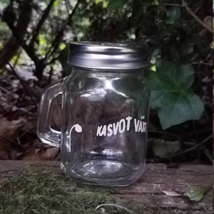 Peut inclure: Un pot en verre transparent avec un couvercle argenté et une poignée. Le pot porte l'inscription "KASVOT VÄXT".