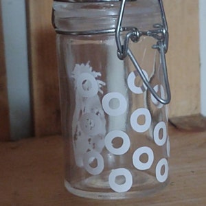 Peut inclure: Un pot en verre transparent avec une fermeture à fermoir métallique. Le pot a un motif de pois blancs.