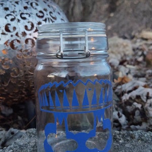 Peut inclure: Un pot en verre transparent avec une couronne bleue et trois cercles bleus sur le devant. Le pot a un couvercle à fermoir métallique.