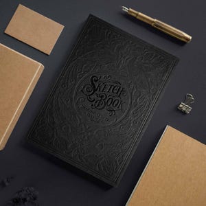 Könnte beinhalten: Schwarzer Skizzenblock mit einem geprägten Blumenmuster und dem Text "Sketch Book Imagine Create Inspire".