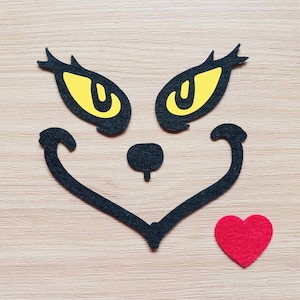 May include: Black felt cutout of a cat face with yellow eyes and a red felt heart.