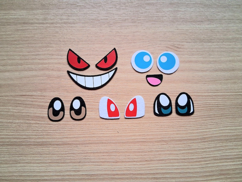 May include: Assortment of cartoon-style face elements, including red angry eyes, a smiling mouth, blue eyes, and various eye pairs. The elements are in different shapes and colors, perfect for crafting or design projects.