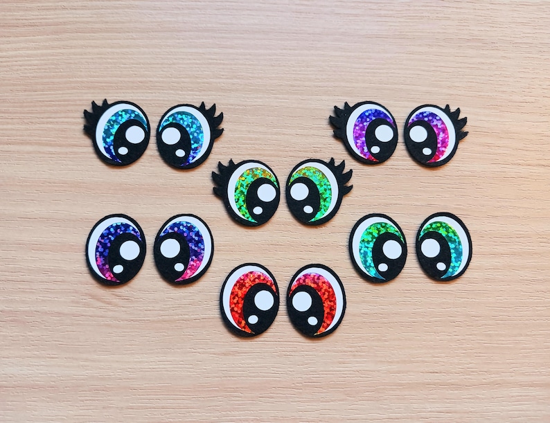 May include: Assortment of colorful googly eyes with black pupils. The eyes are made of glitter and have a shiny finish.