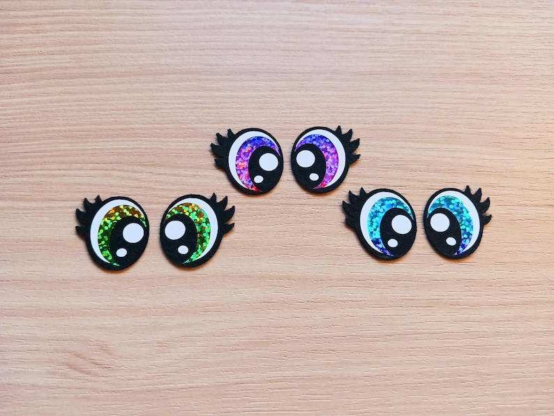 May include: Six colorful googly eyes with black outlines and white pupils. The eyes are made of glitter paper and have a variety of colors, including green, blue, and purple.