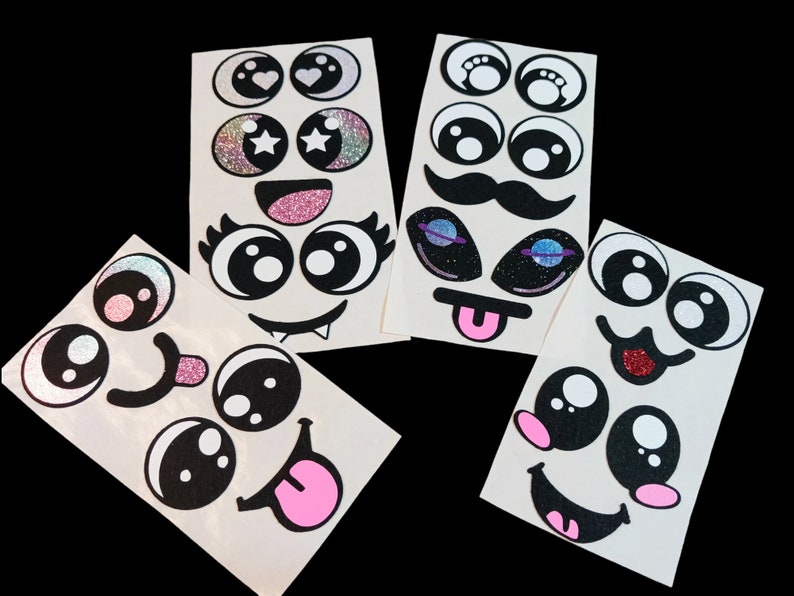 May include: Five sheets of white sticker paper with various black and white cartoon eyes, mouths, and noses. Some of the stickers have glitter accents.