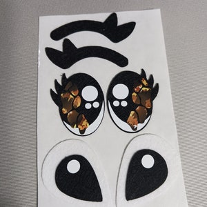 May include: A set of felt eye appliques for crafts. The set includes two pairs of eyes, one pair with a leopard print design and the other pair with a black and white design. The set also includes two pairs of eyelashes.