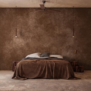 May include: A bedroom scene featuring a bed with a brown blanket and pillows. The room has a brown textured wall, a ceiling fan, and two hanging lights. Wooden side tables and a floor lamp complete the warm, inviting aesthetic.
