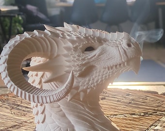 May include: A cream-colored, three-dimensional dragon head sculpture featuring intricate scale textures, a prominent curved horn on the side, and a detailed snout. Wisps of smoke are visible rising from the dragon's nostrils into the air.