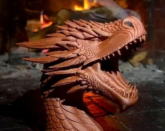 May include: A brown dragon head sculpture featuring intricate scale textures, sharp spikes along the neck, and an open mouth revealing rows of pointed teeth. The figure is rendered in a solid, matte brown material with detailed facial features.