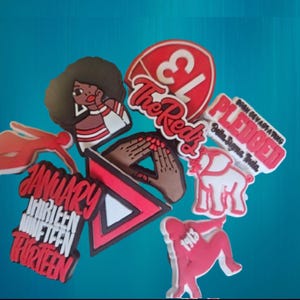 May include: A collection of red, white, and black decorative charms with various designs and text. The charms include an illustration of a woman, hands, an elephant, and the words "The Reds", "Pledged", and "January Thirteen Nineteen Thirteen".