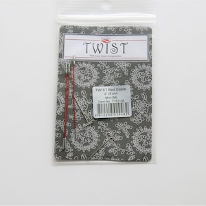 May include: A package of red knitting cables for interchangeable knitting needles. The package includes two 2-inch (5 cm) cables and the text "TWIST Red Cable 2" (5 cm) Mini [M] Item No. 7102-M" is printed on the package.